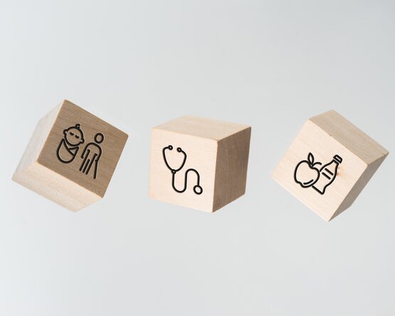 Drei Würfel mit Symbolen zu Benefits am Arbeitsplatz