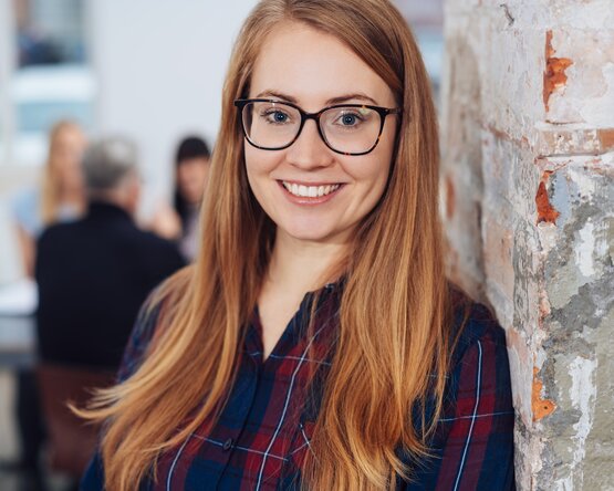 Frau vor Steinmauer mit Blick in die Kamera